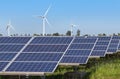 Rows array of polycrystalline silicon solar panels and wind turbines generating electricity in hybrid power plant systems station Royalty Free Stock Photo