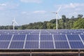 Rows array of polycrystalline silicon solar panels and wind turbines generating electricity in hybrid power plant systems station Royalty Free Stock Photo