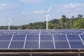 Rows array of polycrystalline silicon solar panels and wind turbines generating electricity in hybrid power plant systems station Royalty Free Stock Photo