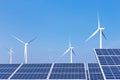 Rows array of polycrystalline silicon solar panels and wind turbines generating electricity in hybrid power plant systems station Royalty Free Stock Photo