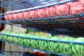 Rows of balls of colorful cotton yarn threads for knitting melange striped pink and green white colors on the shelves in the store Royalty Free Stock Photo