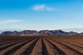 Rows of bare plowed earth in perspective to distant mountains