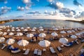 Rows of beach lounges and sun umbrellas on a Coral Bay beach near Peyia village