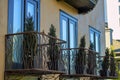 Rows of black decorative metal balconies three visible windows and shrubs with tall stalks in back yard neighborhood