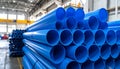 Rows of blue plastic pipes neatly stacked in a large industrial warehouse setting plumbing Royalty Free Stock Photo