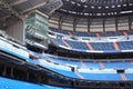 Rows of blue seats for fans at empty stadium.