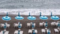 Rows of blue and white parasols and sunbeds on the beach at Atrani on the Amalfi Coast, Italy.