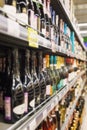 Rows of bottles of alcohol on the shelves in the supermarket. Vertical. Blurred Royalty Free Stock Photo