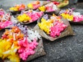 Rows of bright yellow and pink rice offerings in palm leaves