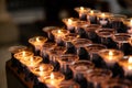 Rows of burning votive candles in a dark European Catholic church in Rome Italy seeking favor from the Lord or saint Royalty Free Stock Photo