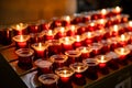 Rows of burning votive candles in a dark European Catholic church in Rome Italy seeking favor from the Lord or saint Royalty Free Stock Photo