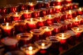 Rows of burning votive candles in a dark European Catholic church in Rome Italy seeking favor from the Lord or saint Royalty Free Stock Photo
