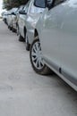 Rows of cars parked on the side of the road in a residential area. Lots of gray cars parallel to the sidewalk. Parallel parking