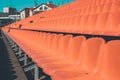 The rows of chairs of orange color leaving in the distance, the tinted photo, plastic seats for the audience under