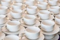 Rows of clean white coffee or tea cups, dish and spoon in a cafeteria or restaurant ready to serve a hot beverage Royalty Free Stock Photo