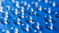 Rows of clear water droplets on a vibrant blue surface with reflective highlights Royalty Free Stock Photo