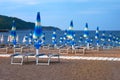 Rows of closed umbrellas and loungers on beach. Happy summer vacations concept. Paid service on beaches Royalty Free Stock Photo