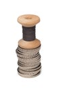 Rows of coins isolated next to multicolored thread on wooden spool