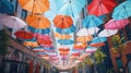 Rows of colorful hanging umbrellas above a street sidewalk with tall trees. Red, yellow, blue, orange, green fabric Royalty Free Stock Photo