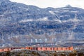 Rows of colorful modern Inuit houses among mossy stones with grey steep slopes of Little Malene mountain in the background, Nuuk,