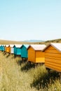 Rows of colorful wooden beehives create a striking visual along the field, surrounded by rolling hills under a clear Royalty Free Stock Photo