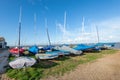 Rows of covered sailboats on land at Whitstable beachfront in Kent, England on a sunny autumn day.