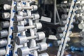 Rows of dumbbells in the gym. Dumbbell set. Close up many metal dumbbells on rack in sport fitness center