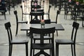 Rows of empty black restaurant terrace tables