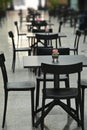 Rows of empty black restaurant terrace tables