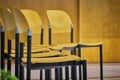 Rows of empty chairs prepared for an indoor event. Chairs made of light brown wood with black metal structure Royalty Free Stock Photo