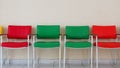 Rows of empty red and green chairs. Plain wall background Royalty Free Stock Photo