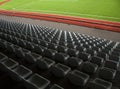 Rows of empty seats in a sports stadium with green grass. Royalty Free Stock Photo