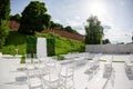 Rows of empty white chairs sitting on a wooden floor. Wedding chairs with flowers at ceremony outdoors Royalty Free Stock Photo