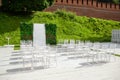 Rows of empty white chairs sitting on a wooden floor. Wedding chairs with flowers at ceremony outdoors Royalty Free Stock Photo