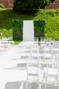 Rows of empty white chairs sitting on a wooden floor. Wedding chairs with flowers at ceremony outdoors Royalty Free Stock Photo