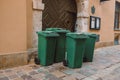 Rows of garbage cans of different colors in an alley in the city center, near a city cafe or restaurant