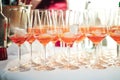 Rows of glasses with orange drink and ice cubes standing on buffet table. Alcoholic beverage. Celebration, birthday