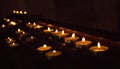 Rows of glowing candles in darkness. Candles with burning falme. Church decoration. Religion and faith background. Royalty Free Stock Photo