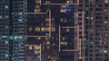 Rows of glowing windows with people in apartment building at night.