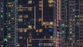 Rows of glowing windows with people in apartment building at night.