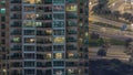 Rows of glowing windows with people in apartment building at night.