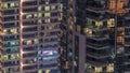 Rows of glowing windows with people in apartment building at night.