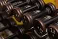 Rows of iron dumbbells on a rack in the gym, old and worn out