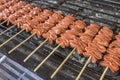 Rows of Isaw or chicken intestine on sticks being cooked on the grill. Isaw is a Filipino delicacy