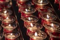 Rows of lit votive candles in a dimly lit room, the church\'s small round candles at Catholics.