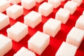 Rows of lump sugar on a brightly red background