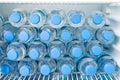Rows of many transparent plastic bottles with drinking water supply in white refrigerator. Mineral water stack storage Royalty Free Stock Photo