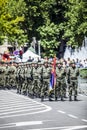 Rows of military troop marching on streets during sunny summer day