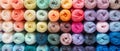 Rows of neatly arranged colorful yarn rolls in bright and pastel shades.