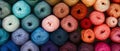Rows of neatly arranged colorful yarn rolls in bright and pastel shades.